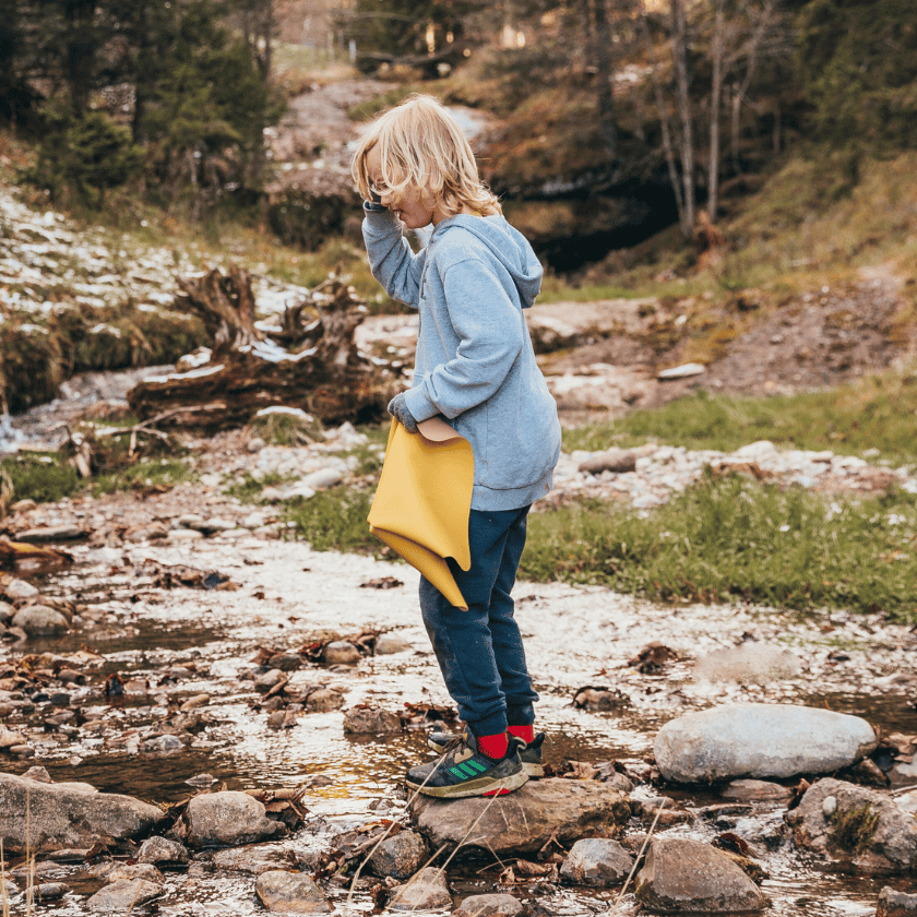 School child in the swiss mountains using a studio huske foldable wriggle mat to sit and snack on 