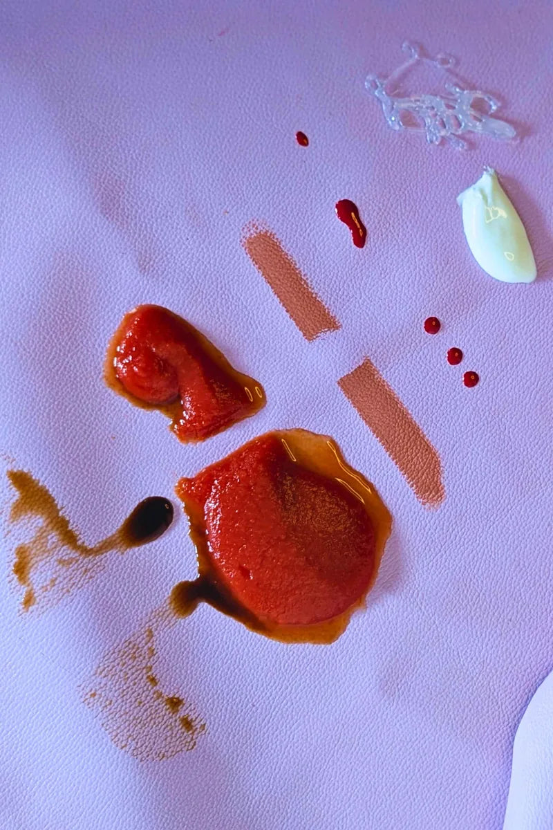 Close-up of Studio Huske silicone leather play mat with tomato sauce and balsamic vinegar stains before cleaning - wipe-clean test