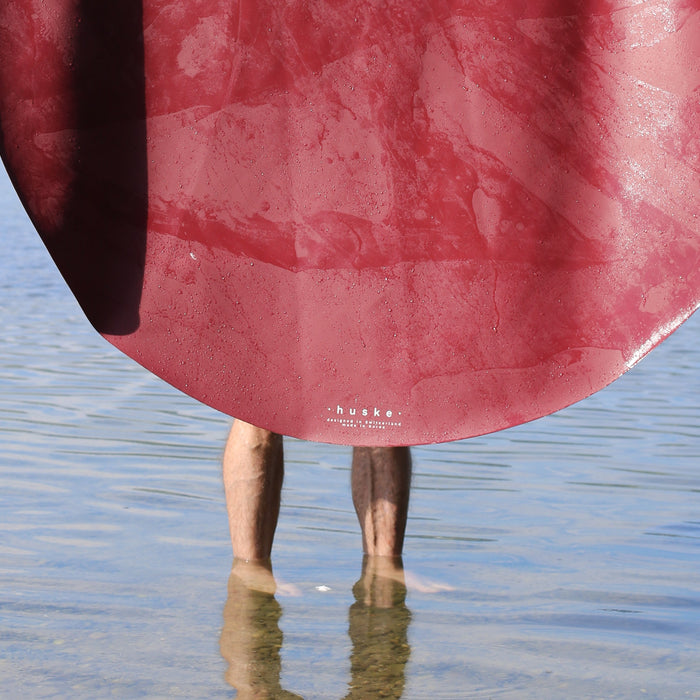 Studio Huske round play mat held dripping over a Swiss lake, hills behind