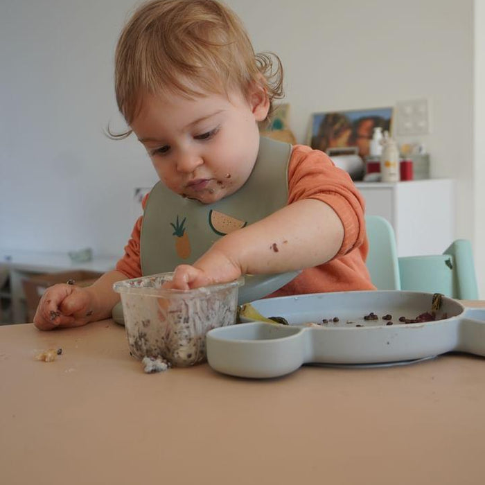 Baby-led weaning toddler with food on face, Studio Huske silicone mat on table 