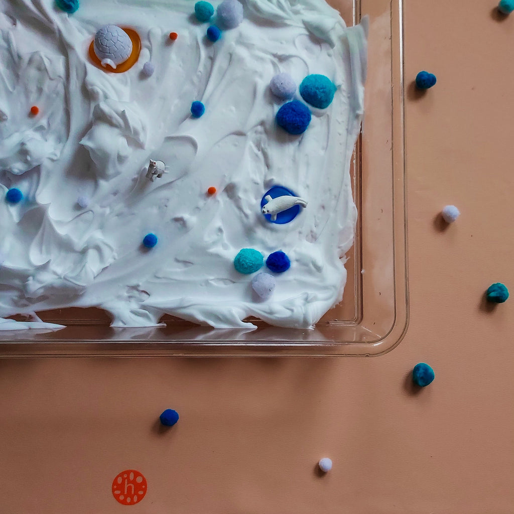 Toddler boy sitting on a sage green Studio Huske silicone leather play mat outdoors