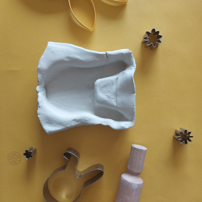 Flat lay on mustard yellow Huske mat with clay models and creative play items