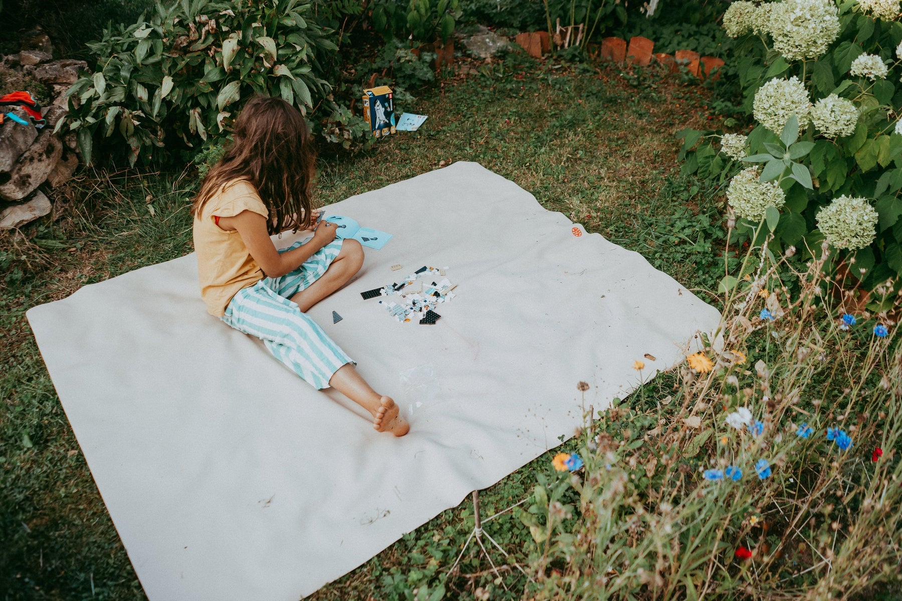 Little girl building Lego on a cream Studio Huske play mat