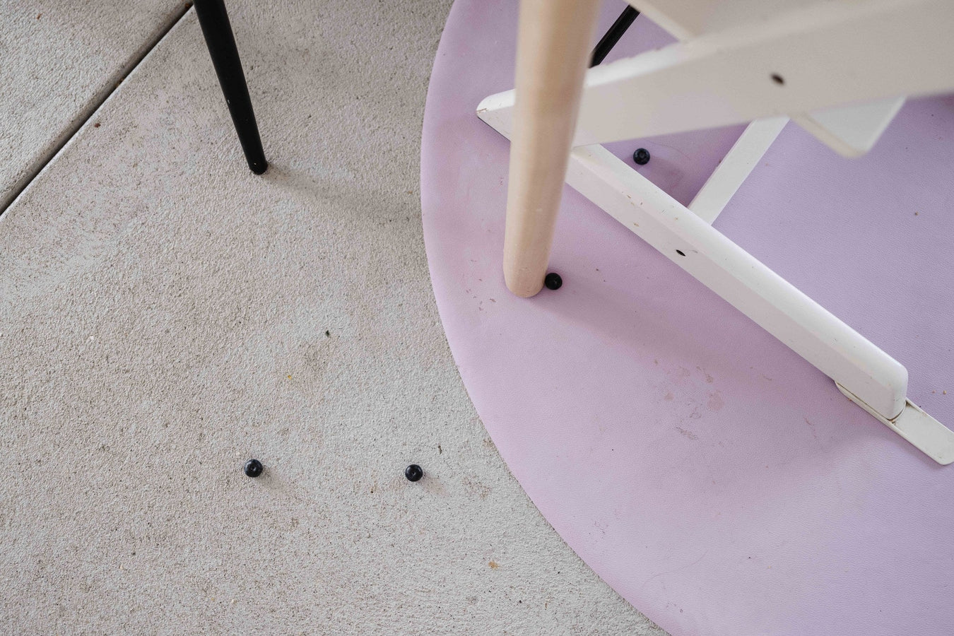 Studio Huske silicone leather floor protection mat on a hard floor with fallen blueberries, showing the wipeable surface