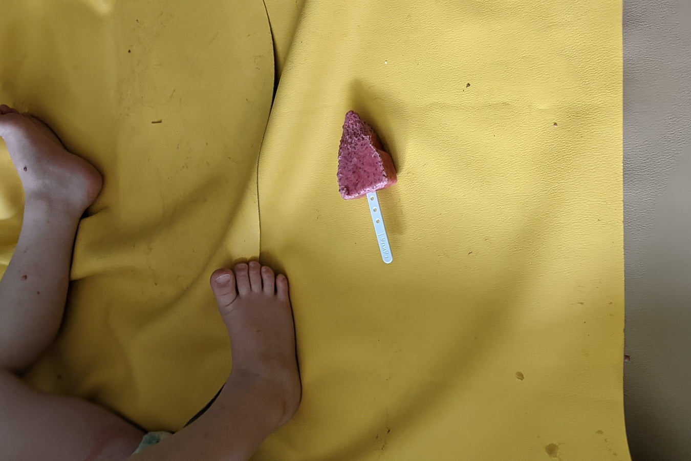 Melting popsicle dropped on yellow silicone wipeable mat showing easy-clean surface