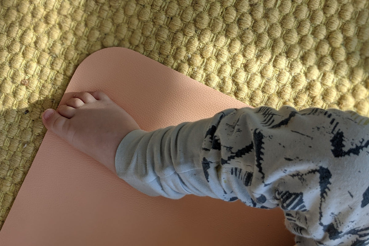 Baby crawling on blush silicone changing mat on jute rug in living room