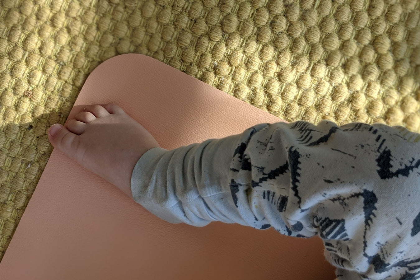 Baby crawling on blush silicone changing mat on jute rug in living room