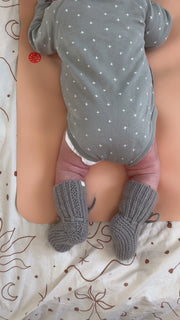 Studio Huske changing mat: newborn in knitted booties lying on a peach mat, seen from above