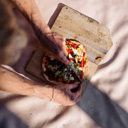 Explore Beige/Wine large round silicone play mat, hands slicing a pizza on a board on the beige mat