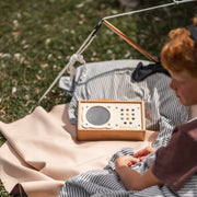 Explore Beige/Wine large round silicone play mat, child listening to a music box beside a tent on the beige mat