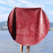 Explore Beige/Wine large round silicone play mat, the whole round mat held up in a lake with the wine face showing