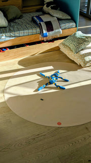 Studio Huske round play mat: wide view of the beige mat on a wooden floor in a child’s bedroom