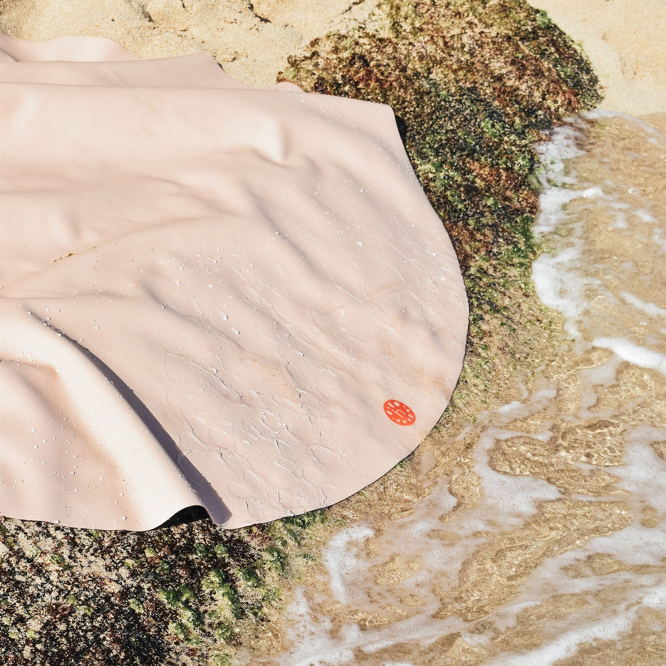 Explore Beige/Wine large round silicone play mat, blush sand huske round mat draped over mossy beach rocks at the