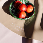 Explore Beige/Wine large round silicone play mat, bowl of tomatoes on the mat beside the logo