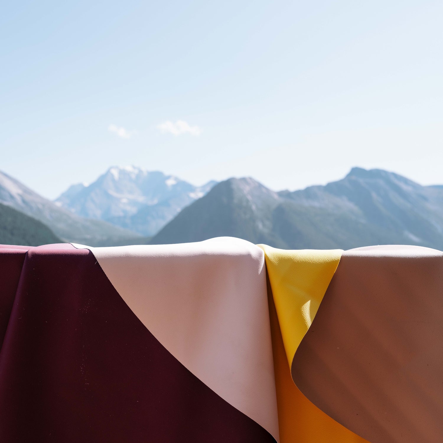 Explore Beige/Wine large round silicone play mat, mats laid out with an alpine valley behind