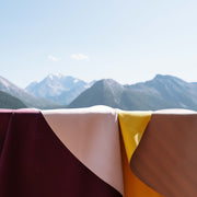 Explore Beige/Wine large round silicone play mat, mats laid out with an alpine valley behind
