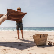 Gallivant XL Silikon-Picknickmatte in Beige/Weinrot, Junge hält die Matte am Strand weit auf, weinrote Seite