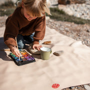 Gallivant XL Silikon-Picknickmatte in Beige/Weinrot, Kind bemalt draussen Steine auf der Matte