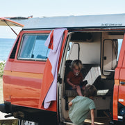 Gallivant XL Lilac/Red silicone family picnic mat, two brothers at red vw westfalia, older boy climbing into van while