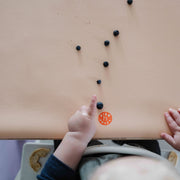 Wriggle Peach/Green silicone changing mat and placemat, baby hands reaching for blueberries on the peach mat