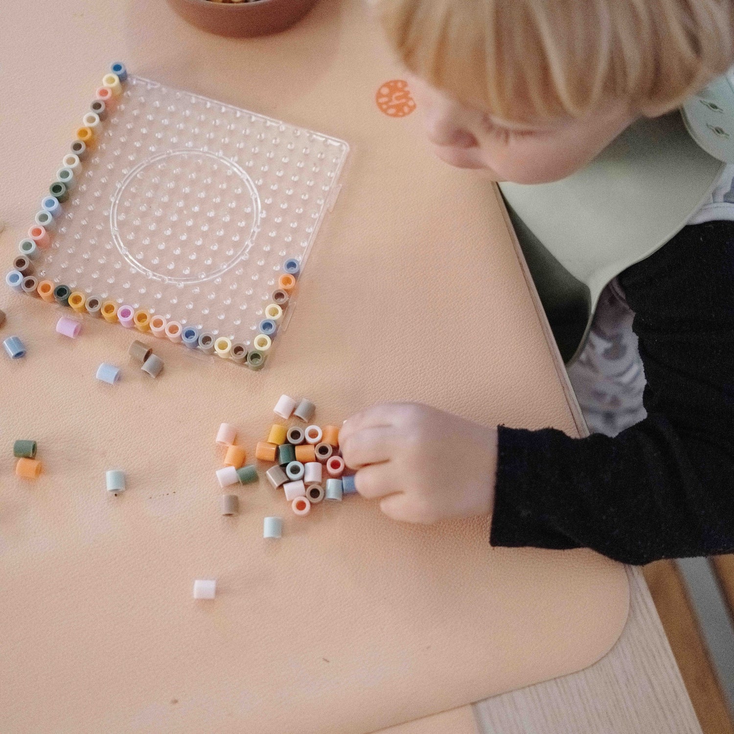 Wriggle Peach/Green silicone changing mat and placemat, toddler sorting perler beads on the peach mat
