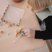 Wriggle Peach/Green silicone changing mat and placemat, toddler sorting perler beads on the peach mat