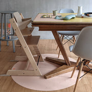 Roam Round Peach/Green silicone splat mat, the peach round mat under a wooden high chair at the dining table