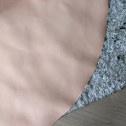 Roam Round Peach/Green silicone splat mat, peach mat edge on a wooden floor beside a grey rug