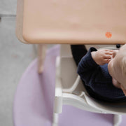 Roam Round Lilac/Red silicone splat mat, child at the high chair with the round mat on the floor beneath