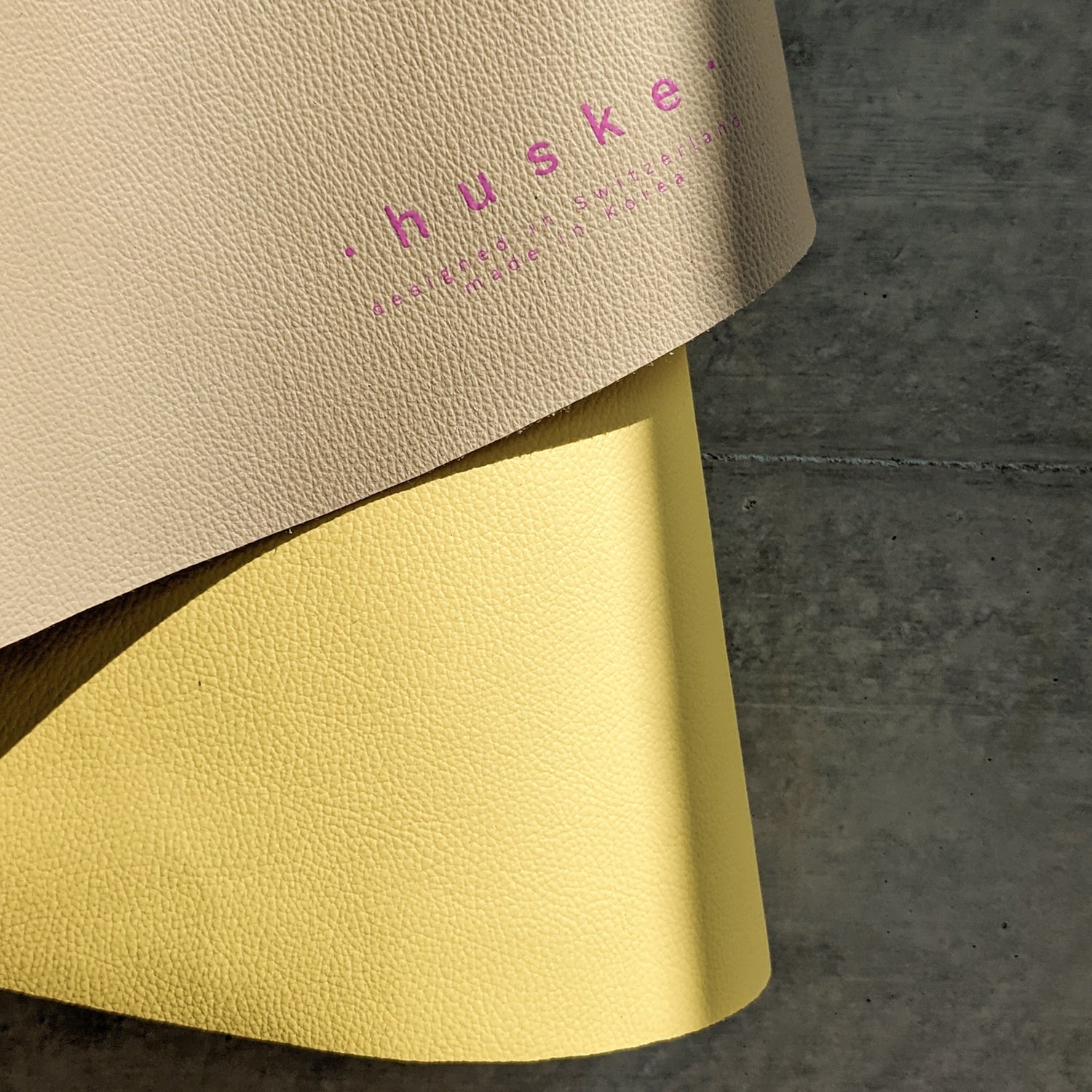 Roam Round Yellow/Mocca silicone splat mat, close view of the mat edge curled to show the logo