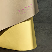 Roam Round Yellow/Mocca silicone splat mat, close view of the mat edge curled to show the logo