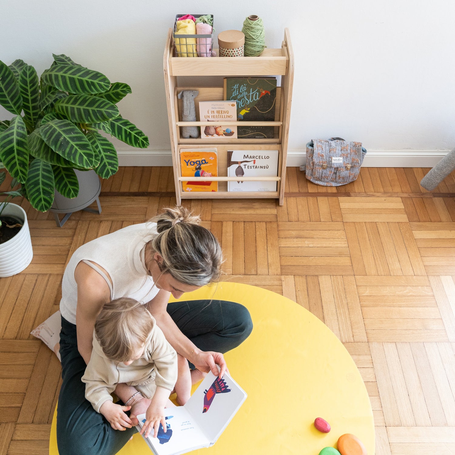 Roam Round Yellow/Mocca silicone splat mat, parent and toddler playing on the round mat in a play corner