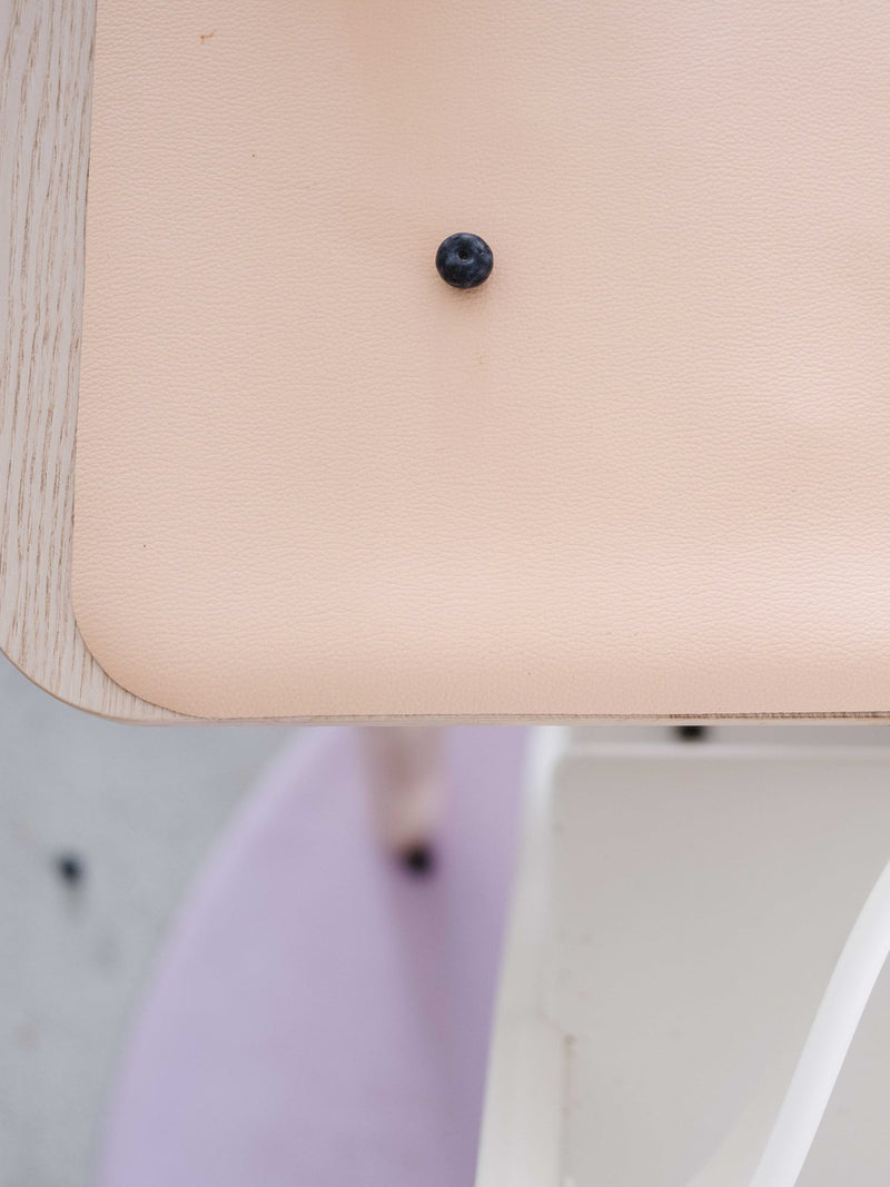 Toddler in a high chair with a peach Huske mat on the table and a lilac round mat on the floor