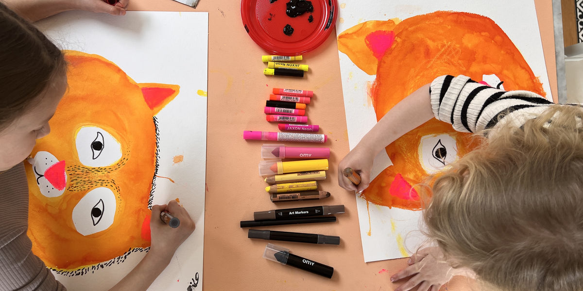 Deux enfants peignent de grands chats orange aux crayons et pastels à l'huile sur un tapis Studio Huske