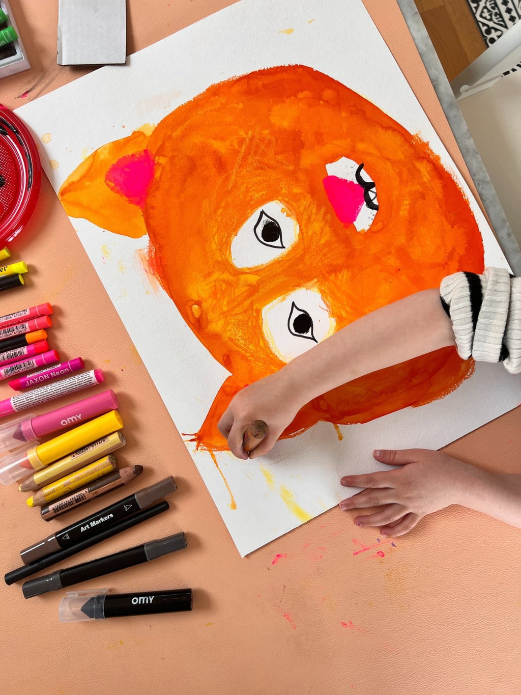 Child painting on Studio Huske mat, close framing shows texture and tools.
