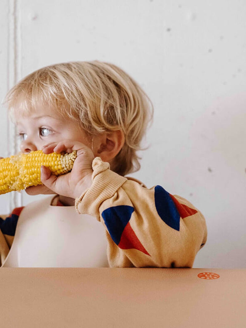 Child sitting on Studio Huske mat in warm natural light.