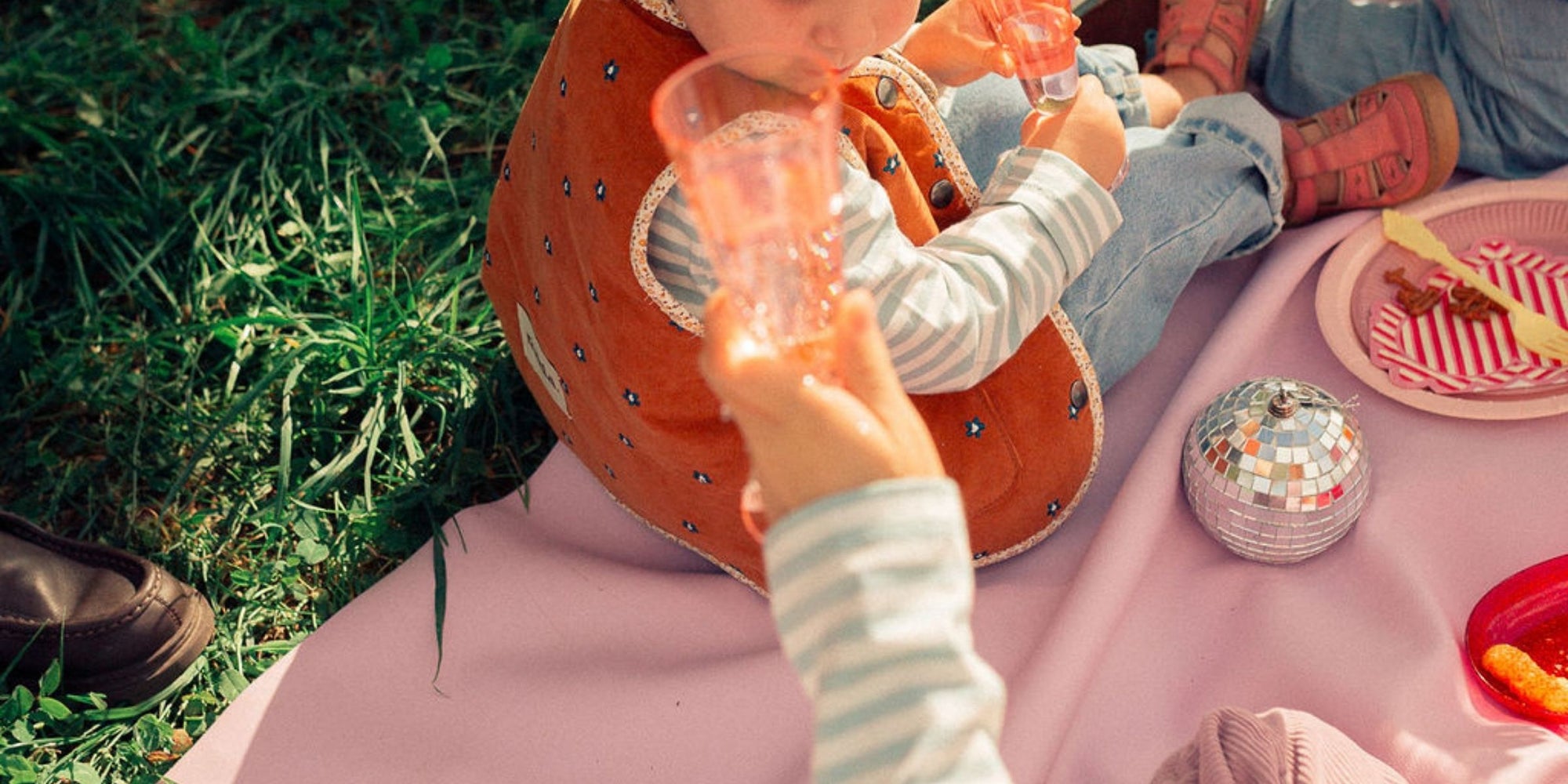 Close-up of hands and food on Studio Huske mat during outdoor picnic.