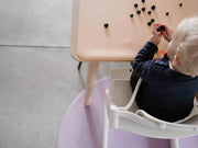 Child playing with toys on a waterproof silicone leather changing mat at a wooden table.
