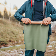 Wriggle Peach/Green silicone changing mat and placemat, adult holding the mat open to show the sage green reverse