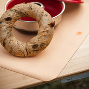 Wriggle Peach/Green silicone changing mat and placemat, bread baked in a camping oven resting on the mat