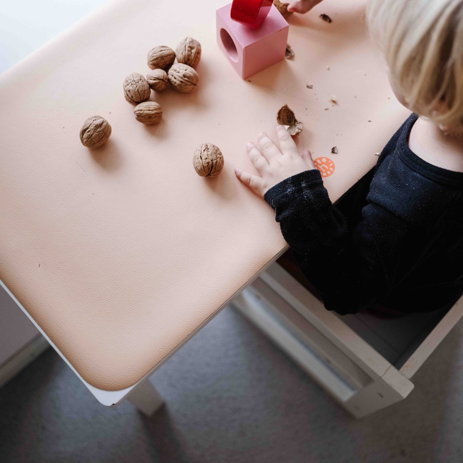 Wriggle Peach/Green silicone changing mat and placemat, child cracking walnuts on the mat at the kids table