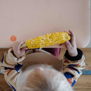 Wriggle Peach/Green silicone changing mat and placemat, toddler eating corn on the cob at the high chair