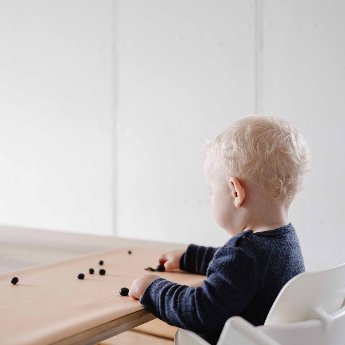 Wriggle Tapis à langer et set de table en silicone pêche/vert, un tout-petit joue avec de petites pièces sur le tapis à table