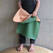Wriggle Tapis à langer et set de table en silicone pêche/vert, un enfant retourne le tapis et montre les deux faces