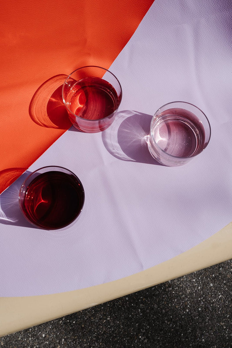 Silicone leather play mat with three glasses in different colors on a vibrant round surface.