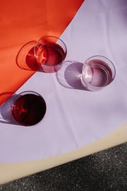 Vegan leather play mat with three glasses in different colors on a vibrant round surface.