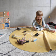 Child playing on a vegan leather play mat surrounded by toys and blocks in a modern indoor setting.