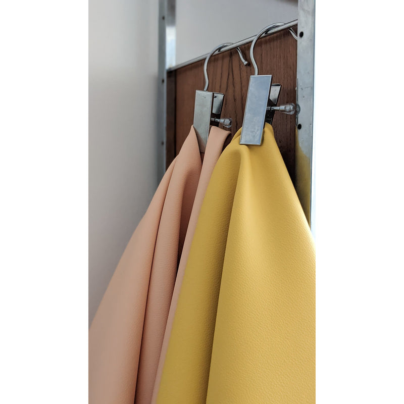 Vegan leather play mat in soft peach and sunny yellow colors hanging on clips.