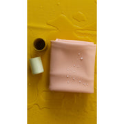 Silicone leather play mat in peach color with water droplets on yellow background, ideal for play activities.