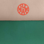 Close-up of silicone leather play mat featuring peach and green colors with a logo detail.